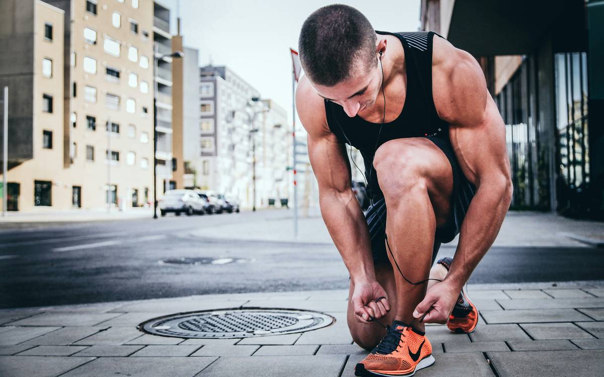 tips to start running: woman smiling while jogging lightly on a sunny suburban sidewalk