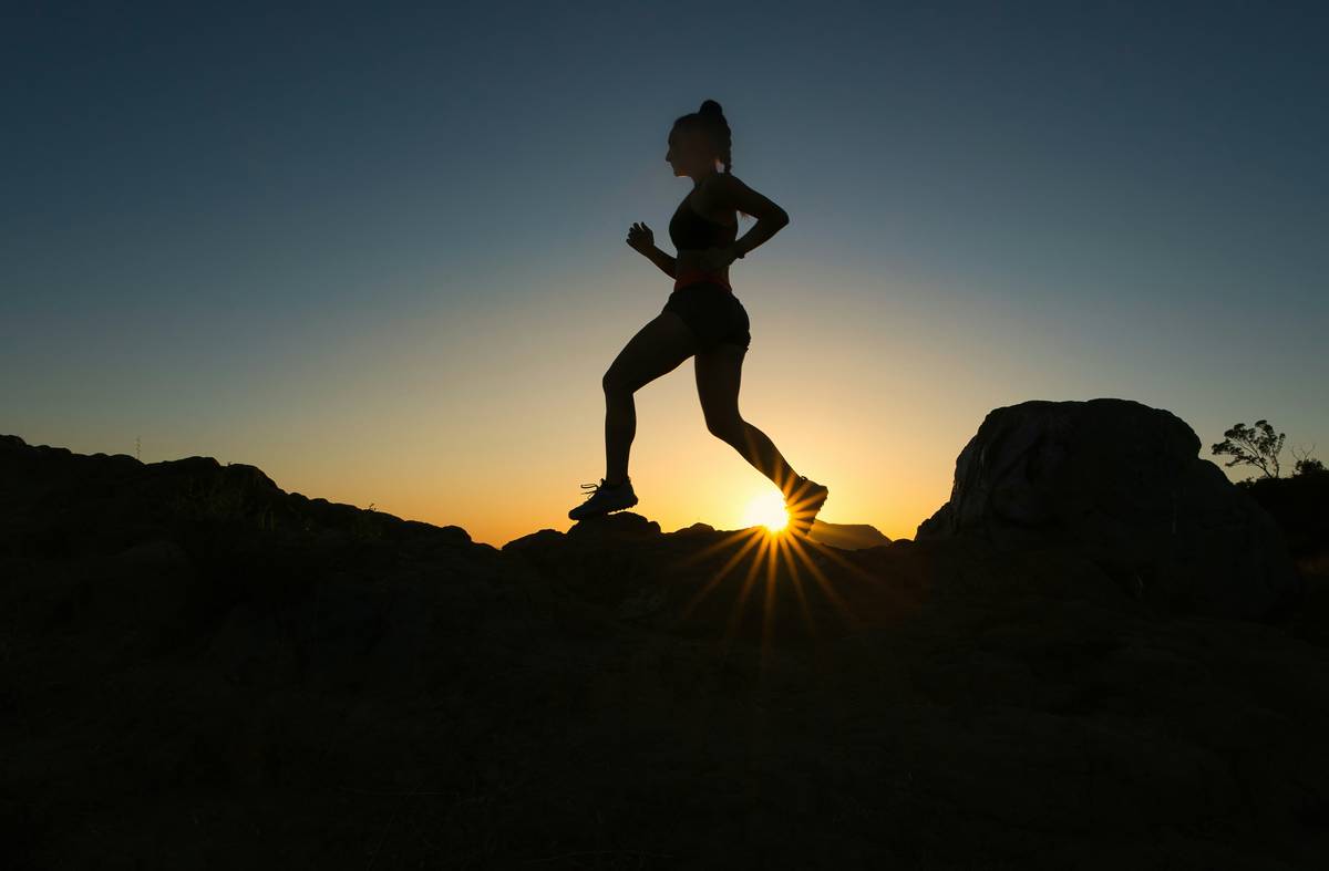 Woman jogging in park at sunrise showcasing benefits from running regularly