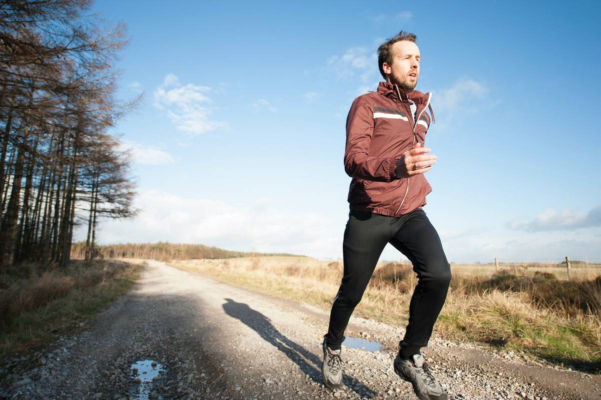 A beginner runner walking and jogging on a park trail during running training for beginners